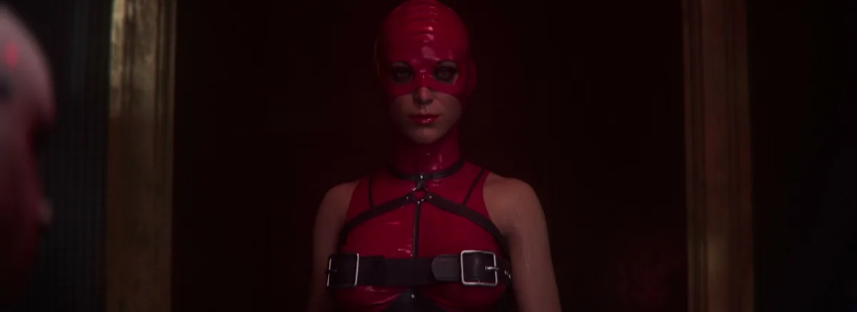 Red-masked cult initiate in latex standing in a dark doorway in Hellraiser: Revival